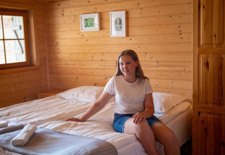 Vrouw zit op een bed in een houten kamer in lodge 'Holiday homes in Miedzyzdroje' in Duitsland.