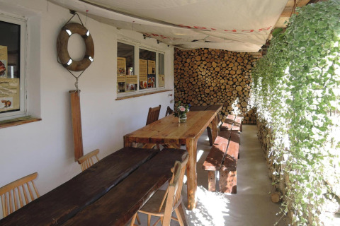 Buiteneetruimte met houten tafels, banken, houtmuur en planten bij Holiday Homes in Miedzyzdroje.