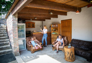 Overdekte zithoek van lodge in Duitsland, houten meubels, twee vrouwen en een kind genieten samen.