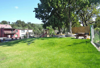 Groen gazon en speeltuin bij Holiday homes in Międzyzdroje, met bomen en picknicktafel buiten.