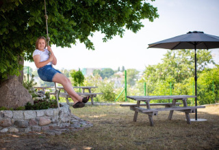 Vrouw op schommel bij picknicktafels en parasol, Holiday homes in Miedzyzdroje, Duitsland.