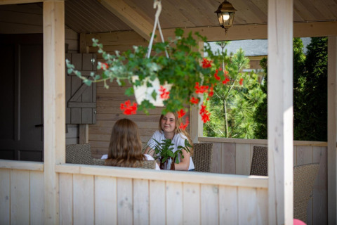 Twee personen zitten op een veranda met hangende bloemen, Holiday homes in Miedzyzdroje in Duitsland.