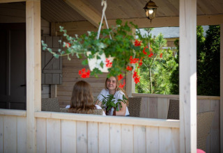 Two people sitting on a porch with hanging flowers at Holiday homes in Miedzyzdroje for 4 persons, Germany.