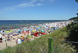Drukke strand met kleurrijke parasols en windschermen bij vakantiehuizen in Miedzyzdroje, Duitsland.