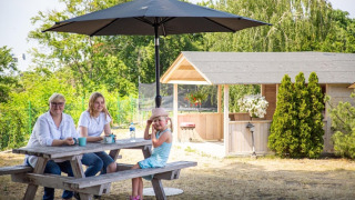 Famiglia al tavolo da picnic sotto ombrellone davanti a casa vacanze per 4 persone Miedzyzdroje, 30 mq Tipo B.