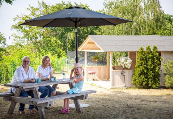 Gezin aan picknicktafel onder parasol voor vakantiewoning voor 4 personen Miedzyzdroje, 30 m² Type B.