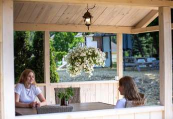 Dos mujeres se sientan en una cabaña de madera con flores colgantes en Holiday homes en Miedzyzdroje, Alemania.