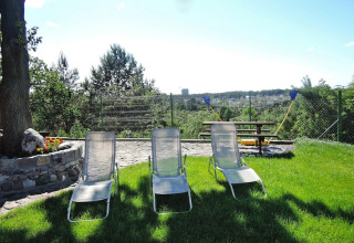 Buitenruimte bij Miedzyzdroje vakantiewoning met ligstoelen, picknickbank en zicht op groene tuin