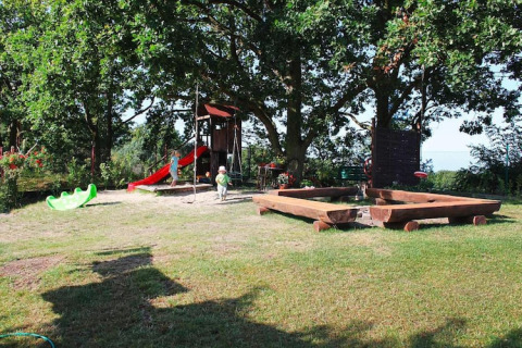 Speeltuin met glijbaan, zandbak en kinderen bij vakantiehuizen in Miedzyzdroje, Duitsland.
