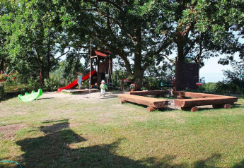 Spielplatz mit Rutsche, Sandkasten und Kindern vor Ferienhäusern in Miedzyzdroje, Deutschland.