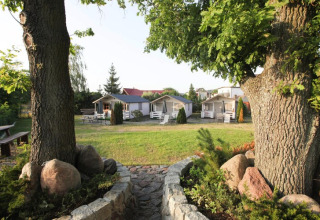 View between two trees onto green lawn and holiday cabins for 4 persons Miedzyzdroje-30 sqm Type B.