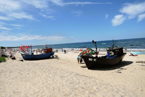 To fiskerbåde på sandstrand med mennesker og havudsigt ved Holiday homes i Miedzyzdroje, Tyskland.