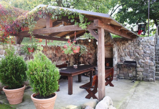 Udendørs terrasse med stenmure, træbord, bænke og planter ved feriehus i Miedzyzdroje, Tyskland.