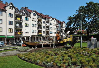 Beeld van visser en boot in park met appartementen op achtergrond, Międzyzdroje, Polen.