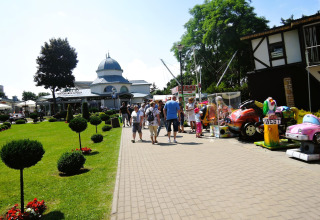 Buitenzicht op vakantiehuizen in Miedzyzdroje met wandelende mensen, speeltoestellen en restaurant op de achtergrond.