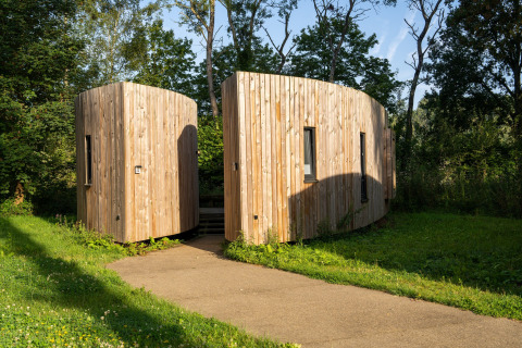 Modern wooden tiny house, 'The Lodge by YourNature,' surrounded by greenery in Belgium.