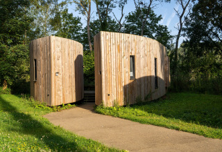 Modern wooden tiny house, 'The Lodge by YourNature,' surrounded by greenery in Belgium.