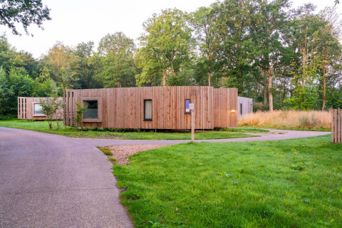 Moderne tiny house med træfacade i grønne omgivelser og natur, omgivet af stier og træer.