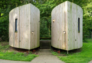 Two modern wooden tiny houses, The Lodge by YourNature, set in a lush green forest environment.
