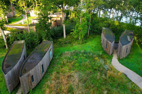 Luftfoto af unikke tiny houses kaldet The Lodge ved YourNature, omgivet af grøn natur og skov.