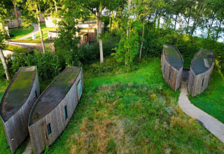 Aerial view of unique tiny houses named The Lodge by YourNature, nestled in greenery and forest trees.