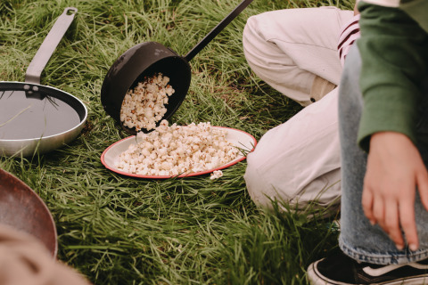 Kinder machen Popcorn im Gras bei Feather Down De Oude Melkstal, einem Ferienpark in Nordbrabant, Niederlande.