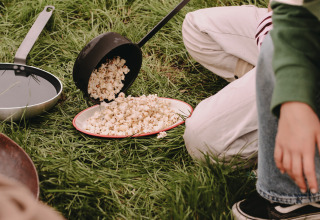 Kinderen bereiden popcorn op gras bij Feather Down De Oude Melkstal, een vakantiepark in Noord-Brabant, Nederland.