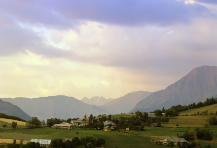Paisaje rural cerca de Méolans-Revel en Provence-Alpes-Côte d’Azur, con campos, aldeas y montañas al fondo.