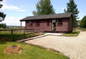 Foto dello chalet Five Waterings: casetta in legno, giardino recintato e vialetto in ghiaia in campagna.
