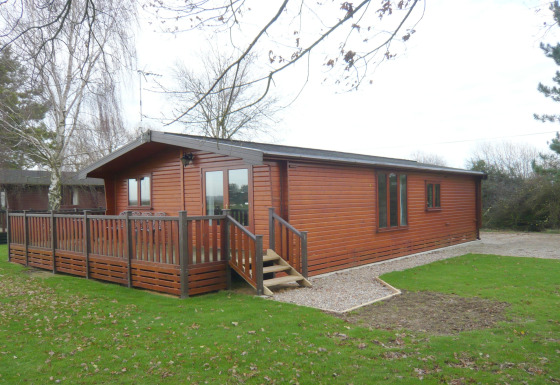 Foto del lodge Rainbow Petty con esterno in legno, veranda, prato verde e alberi tutt’intorno.