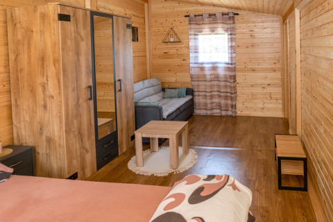 Gezellige houten bungalowkamer met bank, kledingkast en tafel bij Robinzonski Kamp Hofman, Kroatië.
