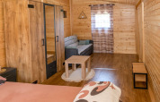 Accogliente bungalow in legno con divano, armadio e tavolino presso Robinzonski Kamp Hofman, Croazia.