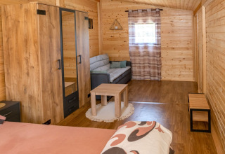 Gezellige houten bungalowkamer met bank, kledingkast en tafel bij Robinzonski Kamp Hofman, Kroatië.