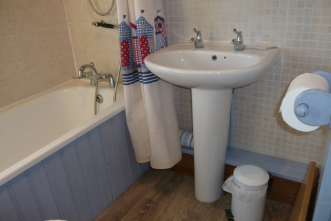 Et kompakt badeværelse på Five Waterings med badekar, forhæng, håndvask, toiletspand og toiletrulle.