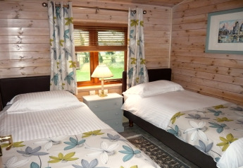 Dormitorio acogedor con dos camas individuales, decoración floral y vista al jardín en Rainbow Petty Lodge, Reino Unido.