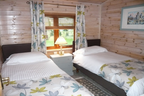 Camera con due letti singoli, decorazione floreale e vista giardino al Rainbow Petty Lodge nel Regno Unito.