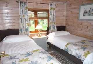 Camera con due letti singoli, decorazione floreale e vista giardino al Rainbow Petty Lodge nel Regno Unito.