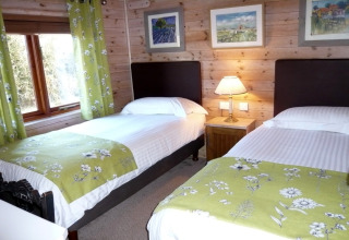 Accogliente camera doppia con accenti verdi floreali e pareti di legno al Rainbow Petty lodge nel Regno Unito.