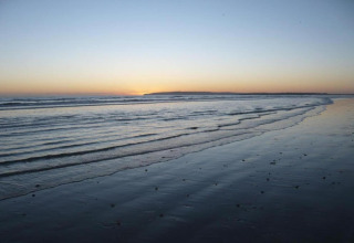 Tramonto sul mare visto dalla spiaggia presso Rainbow Petty Lodge nel Regno Unito, atmosfera tranquilla.