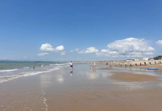 Scena di spiaggia presso il lodge Rainbow Petty nel Regno Unito, persone e mare sotto cielo sereno.