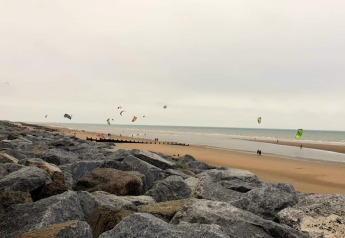 Vista de una playa rocosa con cometas y kitesurf en la costa tomada desde Rainbow Petty en el Reino Unido.