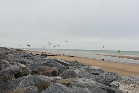 Vista di una spiaggia rocciosa con aquiloni e kitesurfer, scattata da Rainbow Petty nel Regno Unito.