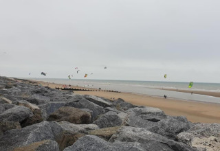 Vista di una spiaggia rocciosa con aquiloni e kitesurfer, scattata da Rainbow Petty nel Regno Unito.