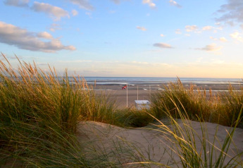 Vista de playa con dunas y pasto al atardecer desde Rainbow Petty lodge en el Reino Unido.