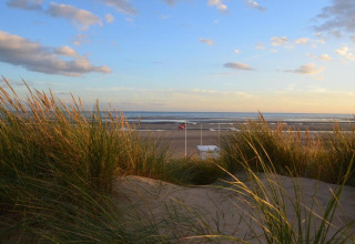 Vista sulla spiaggia con dune e erba al tramonto dalla Rainbow Petty lodge nel Regno Unito.