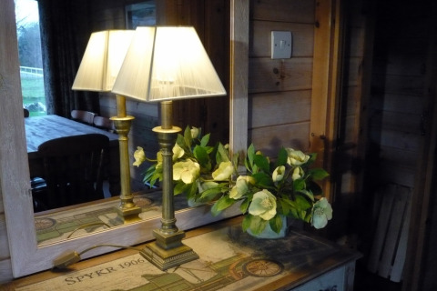 Lampada e fiori su un tavolo davanti a uno specchio, riflettendo l’interno della Rainbow Petty lodge nel Regno Unito.