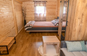 Accogliente bungalow in legno con letto matrimoniale, divano e tavolino al Robinzonski Kamp Hofman, Croazia.