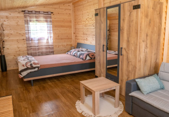 Interior of a mobile home at Robinzonski Kamp Hofman, Croatia, with wood walls, bed, wardrobe and sofa.