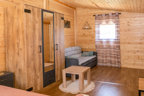 Interieur van Robinzonski Kamp Hofman mobiele bungalow in Kroatië met bank, kast en houten muren.