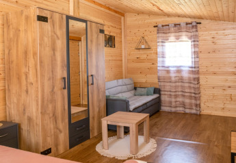 Interno della casa mobile Robinzonski Kamp Hofman in Croazia con divano, armadio e pareti in legno.